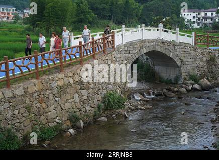 220731 -- JING AN, 31. Juli 2022 -- Touristen machen einen Spaziergang im Dorf Sanping der Stadt Zhongyuan im Kreis Jing an, ostchinesische Provinz Jiangxi, 27. Juli 2022. Die Stadt Zhongyuan in der ostchinesischen Provinz Jiangxi liegt auf einer Höhe von über 600 Metern und hat eine Waldbedeckungsrate von fast 90 %. Infolgedessen ist die Durchschnittstemperatur hier 6 bis 10 Grad kühler als die des nahegelegenen Nanchang, der Hauptstadt der Provinz Jiangxi, was die Stadt zu einem günstigen Sommerresort für Touristen macht, die der Sommerhitze entfliehen. Dieser Ort war früher von Armut betroffen, und wir haben unseren Lebensunterhalt dadurch verdient, dass wir den Bam abbrachen Stockfoto