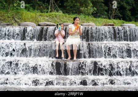 220731 -- JING AN, 31. Juli 2022 -- Kinder spielen mit Wasserwaffen im Dorf Sanping der Stadt Zhongyuan im Kreis Jing an, ostchinesische Provinz Jiangxi, 27. Juli 2022. Die Stadt Zhongyuan in der ostchinesischen Provinz Jiangxi liegt auf einer Höhe von über 600 Metern und hat eine Waldbedeckungsrate von fast 90 %. Infolgedessen ist die Durchschnittstemperatur hier 6 bis 10 Grad kühler als die des nahegelegenen Nanchang, der Hauptstadt der Provinz Jiangxi, was die Stadt zu einem günstigen Sommerresort für Touristen macht, die der Sommerhitze entfliehen. Dieser Ort war früher von Armut betroffen, und wir haben unseren Lebensunterhalt mit der Kürzung von Geld verdient Stockfoto