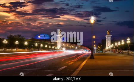 Verkehr auf Alexandre III Brücke in Paris bei Sonnenuntergang Stockfoto