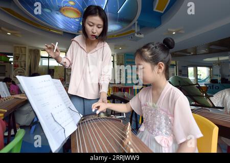 220811 -- HEFEI, 11. August 2022 -- Schüler lernen Guzheng oder chinesische Zither in Hefei, ostchinesische Provinz Anhui, 10. August 2022. Einige Schulen in Hefei bieten in diesem Sommer kostenlose Kindertagesstätten für Schüler an. Die Kindertagesbetreuung hilft nicht nur den Schülern, die Sommerzeit zu bereichern, sondern verringert auch den Druck auf berufstätige Eltern, die ansonsten während des Urlaubs auf ihre Kinder aufpassen müssen. CHINA-ANHUI-HEFEI-TAGESBETREUUNG CN ZHOUXMU PUBLICATIONXNOTXINXCHN Stockfoto