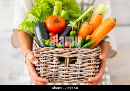 Nicht erkennbarer Besitzer eines Gemüseladens, der einen Korb voller farbenfroher saisonaler Gemüsesorten hält. Gesundes Lifestyle- und Hofhauskonzept. Vitamine und Gesundheit Ernährung Lebensweise Menschen. Diät Gewichtsabnahme Vegetarisch Stockfoto