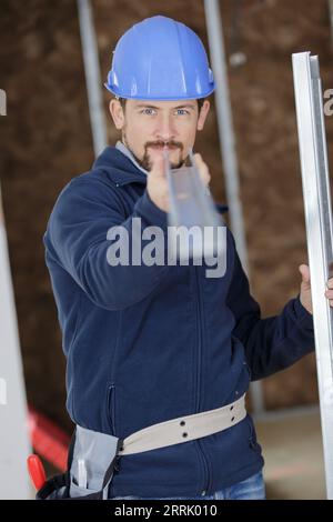Männlicher Arbeiter, der prüft, ob die Länge des Metalls gerade ist Stockfoto