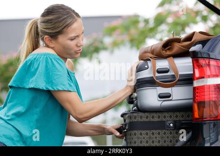 Junge Frau, die Gepäck in den hinteren Teil des Autos lädt Stockfoto