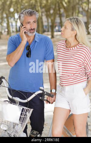 Glückliches reifes Paar, das ein Telefon im Park benutzt Stockfoto