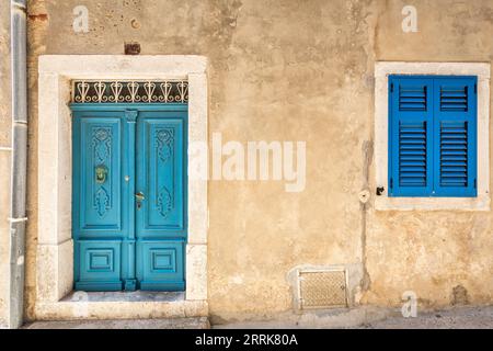 Kroatien, Primorje-Gorski Komitat Kotar, Insel Krk, Details eines Hauses in Baska mit türkisfarbener Eingangstür und azurblauem Fenster Stockfoto