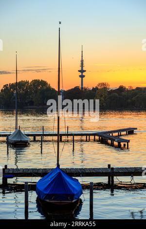 Hamburg, Äußere Alster nach Sonnenuntergang, Segelboote liegen auf dem Steg, Fernsehturm im Hintergrund, orange-roter Himmel, Stockfoto