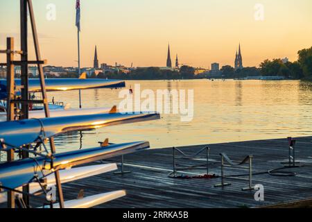 Hamburg, Außenalster bei Sonnenuntergang, Bootssteg mit Ruderbooten im Vordergrund, Skyline von Hamburg im Hintergrund, Stockfoto