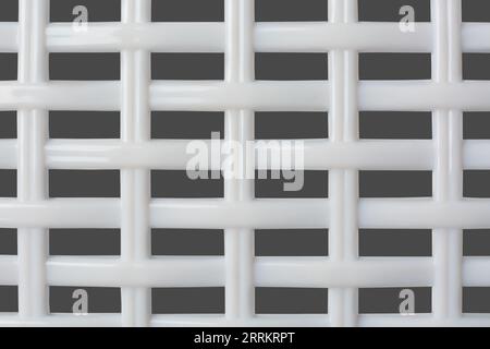Nahaufnahme der abstrakten, weißen geometrischen Hintergrundtextur des Kunststoffgitters für das Entwerfen, Netzmusterstruktur im gesamten Rahmen isoliert auf Grau Stockfoto