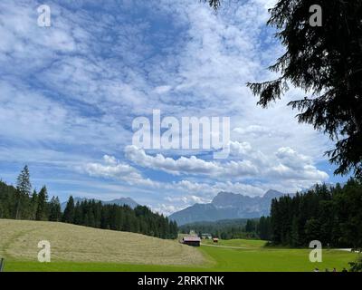 Blick über Wiese und Scheune im Elmautal auf Schloss Kranzbach und Karwendel mit Soierngebirge, Oberes Isartal, Alpenwelt Karwendel, Wetterstein, Sonne, Berge, Wolken, Natur, Aktivität, Werdenfelser Land, Oberbayern, Deutschland Stockfoto