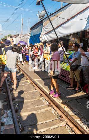 Touristen, die im Zug warten, Essen auf der Schiene verkaufen, Maeklong Railway Market, Talad Rom Hub Railway Market, in der Nähe von Bangkok, Samut Songkhram, Thailand, Asien Stockfoto