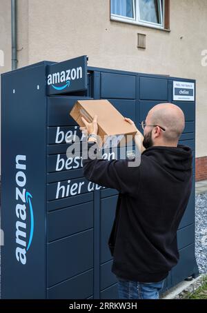 Bottrop, Nordrhein-Westfalen, Deutschland – Amazon, Amazon Locker, Amazon Hub, Packstation, Paketstation, Abholstation, Kunde holt Paket ab, ein Kunde öffnet eine Klappe mit einer App auf seinem Handy und nimmt sein Paket heraus. Stockfoto