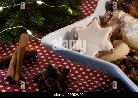 Weihnachtlich geschmückte Weihnachtskekse. Lebkuchen, Zimtsterne, Vanillesichel und Makronen. Dekoriert mit Tannen, Feenlichtern und Zimt Stockfoto