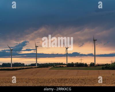 Windturbinen in Thüringen mit abfahrendem Gewitter im Sonnenuntergang. Stockfoto