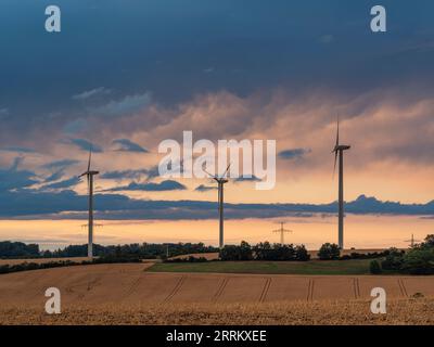 Windturbinen in Thüringen mit abfahrendem Gewitter im Sonnenuntergang. Stockfoto