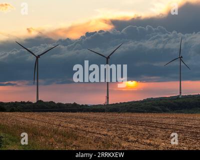 Windturbinen in Thüringen mit abfahrendem Gewitter im Sonnenuntergang. Stockfoto