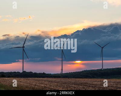 Windturbinen in Thüringen mit abfahrendem Gewitter im Sonnenuntergang. Stockfoto