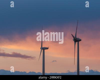 Windturbinen in Thüringen mit abfahrendem Gewitter im Sonnenuntergang. Stockfoto