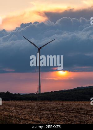 Windturbinen in Thüringen mit abfahrendem Gewitter im Sonnenuntergang. Stockfoto