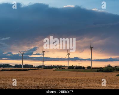 Windturbinen in Thüringen mit abfahrendem Gewitter im Sonnenuntergang. Stockfoto