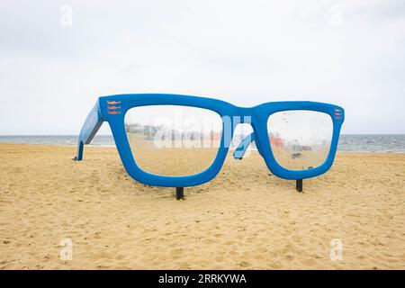 Riesige blaue Sonnenbrille am Scheveningen Beach, Niederlande, um Fotos mit Menschen zu machen. Stockfoto