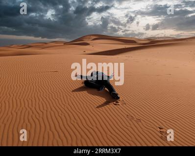 Eine Person, die vorgibt, tot in der Erg Chebbi Wüste in Marokko zu liegen Stockfoto