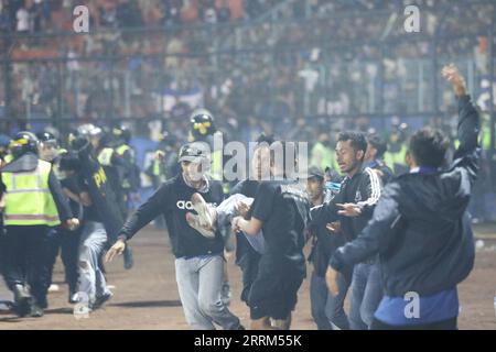 Indonesien, Massenpanik während eines Fußballspiels in Provinz Ost-Java 221002 -- MALANG, 2. Oktober 2022 -- Menschen verlegen einen Verletzten im Kanjuruhan-Stadion in Malang der Provinz Ost-Java, Indonesien, 1. Oktober 2022. Die Zahl der Todesopfer in einer Menschenmenge bei einem Fußballspiel in der indonesischen Provinz Ost-Java hat laut dem stellvertretenden Gouverneur der Provinz Emil Dardak am Sonntagnachmittag 174 erreicht. Die Tragödie ereignete sich am Samstagabend im Kanjuruhan-Stadion in Malang in der indonesischen Provinz Ost-Java, unmittelbar nachdem der Verein AREMA Malang gegen Persebaya Surabaya in einer indonesischen Liga verloren hatte Stockfoto