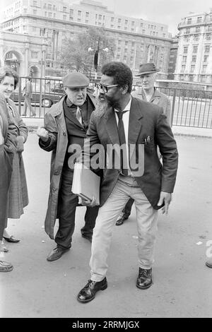 London. 1965: Ein Evangelist predigt in Speaker’s Corner, Hyde Park an der Kreuzung von Cumberland Gate, in der Nähe von Marble Arch, London. Der Prediger hält eine Bibel in der Hand und eine Gruppe von Zuschauern hat sich um ihn versammelt. Ein älterer Mann, der einen Regenmantel und eine flache Kappe trägt, ballt seine Faust und verspottet den Prediger. Marble Arch und das Cumberland Hotel sind in der Ferne zu sehen. Stockfoto