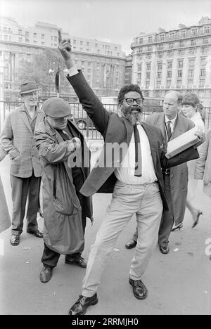 London. 1965: Ein Evangelist predigt in Speaker’s Corner, Hyde Park an der Kreuzung von Cumberland Gate, in der Nähe von Marble Arch, London. Der Prediger hält eine Bibel in der einen Hand und zeigt mit der anderen in den Himmel. Eine Gruppe von Zuschauern hat sich um ihn herum versammelt. Das Cumberland Hotel und das Gebäude an der 140 Park Lane sind in der Ferne zu sehen. Stockfoto