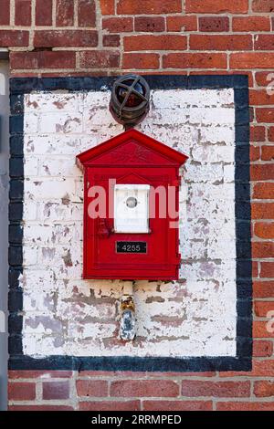 Die traditionelle Bostoner Feuerwehranlage - hergestellt von Game Well - wurde an einer alten Backsteinmauer montiert Stockfoto