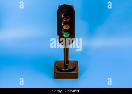 Miniatur-Verkehrsampel mit rotem, orangefarbenem und grünem Licht aus. Studio-Aufnahme. Himmelblau leerer Hintergrund. Stockfoto