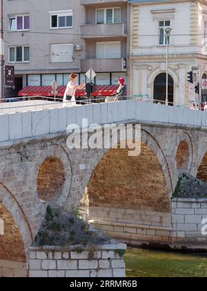 Schleppen Sie Frauen auf der berühmten Latin Bridge über die Rivrer Miljacka an einem Sommertag in Sarajevo, Bosnien und Herzegowina, 08. September 2023 Stockfoto