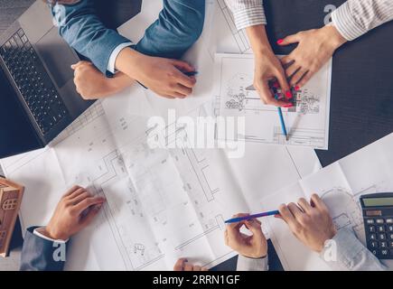 Manager sitzen im Büro und besprechen die Zeichnungen des Hauses. Stockfoto