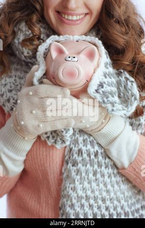 Hallo Winter. Nahaufnahme auf trendigen Frauen in Pullover, Fäustlingen, Hut und Schal mit Schweinebank isoliert auf weiß. Stockfoto