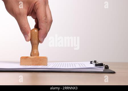 Mann stempelt Dokumente am Holztisch, Nahaufnahme. Leerzeichen für Text Stockfoto