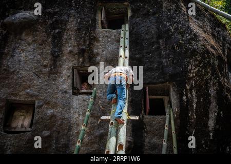 Nord-Toraja, Indonesien. September 2023. Ein Familienmitglied besucht die Gräber von Verwandten während eines traditionellen Rituals namens „Manene“ auf dem Lokomata-Steinfriedhof. Das Ritual findet alle drei Jahre statt, wenn sich Familienmitglieder versammeln, um die Gräber zu reinigen und die Kleidung ihrer verstorbenen Verwandten zu ändern, um ihre Geister zu ehren. Quelle: SOPA Images Limited/Alamy Live News Stockfoto