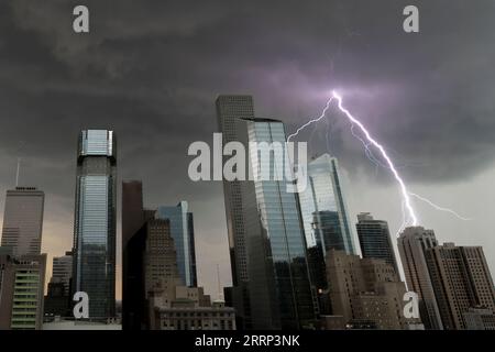 Ein Blitz, der aus den Wolken über der Skyline der Innenstadt von Houston herausragt und ein Bürogebäude zu treffen scheint. Foto von Bob Gwaltney. Stockfoto