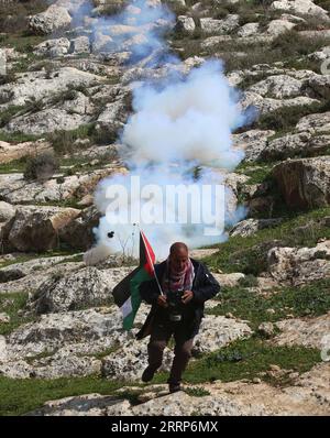 230224 -- BEIT DAJAN, 24. Februar 2023 -- Ein palästinensischer Demonstrant entkommt einem von einem israelischen Soldaten gefeuerten Tränengaskanister, nachdem er am 24. Februar 2023 gegen die Expansion jüdischer Siedlungen im Dorf Beit Dajan östlich von Nablus protestiert hatte. Die Frage jüdischer Siedlungen im Westjordanland und in Ostjerusalem ist seit langem eine wichtige Quelle von Streitigkeiten zwischen Israelis und Palästinensern. Foto von /Xinhua MIDEAST-BEIT DAJAN-CLASHES NidalxEshtayeh PUBLICATIONxNOTxINxCHN Stockfoto