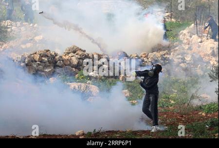 230224 -- BEIT DAJAN, 24. Februar 2023 -- Ein palästinensischer Demonstrant wirft einen Tränengaskanister zurück, der am 24. Februar 2023 von einem israelischen Soldaten während der Zusammenstöße nach einem Protest gegen die Expansion jüdischer Siedlungen im Dorf Beit Dajan im Westjordanland östlich von Nablus gefeuert wurde. Die Frage jüdischer Siedlungen im Westjordanland und in Ostjerusalem ist seit langem eine wichtige Quelle von Streitigkeiten zwischen Israelis und Palästinensern. Foto von /Xinhua MIDEAST-BEIT DAJAN-CLASHES NidalxEshtayeh PUBLICATIONxNOTxINxCHN Stockfoto