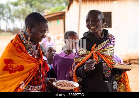 230301 -- KAJIADO, 1. März 2023 -- Mitglieder einer Maasai-Familie halten Teller mit ihrem Mittagessen in einem Internat im Kajiado County, Kenia, 28. Februar 2023. Die Maasai sind eine nilotische ethnische Gruppe, die in Zentral- und Südkenien und im Norden Tansanias lebt. Sie verlassen sich auf die Viehzucht als Haupteinnahmequelle. Nach einer historischen fünften in Folge gescheiterten Regenzeit am Horn von Afrika wurde das Leben von Maasais in Kenia schwer beeinträchtigt, da zahlreiche ausgemergelte Tiere aufgrund von Futtergrasknappheit und Wassermangel ums Leben kamen. KENYA-KAJIADO-DÜRRE-MAASAIS-LIFE LIXYAHUI P Stockfoto