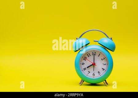 Zeitkonzept mit blauer Uhr auf gelbem Hintergrund Stockfoto