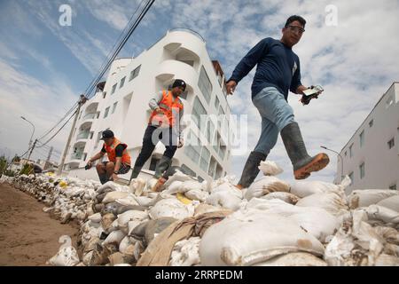 230317 -- LIMA, 17. März 2023 -- Menschen gehen auf einer temporären Barriere, die gebaut wurde, um Erdrutsche durch starken Regen in Punta Hermosa, Peru, zu verhindern, 16. März 2023. Der Zyklon Yaku hat in den letzten Tagen Regenströme in der nördlichen Region Perus ausgelöst. Foto von /Xinhua PERU-LIMA-CYCLONE YAKU-AFTERMATH MarianaxBazo PUBLICATIONxNOTxINxCHN Stockfoto
