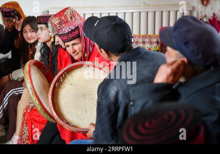 230322 -- TAXKORGAN, 22. März 2023 -- Verwandte und Freunde der Braut Gulihan Jrbli spielen Tambourine und singen in ihrem Haus im autonomen Kreis Taxkorgan Tadschik, Nordwestchina Xinjiang Uygur Autonomous Region, 18. März 2023. Im autonomen Kreis Taxkorgan Tadschik ziehen es viele junge Männer und Frauen vor, im Frühjahr zu heiraten. Vor kurzem feierten die 25-jährige Gulihan Jrbli und ihr Bräutigam Mairmaitih Tirmur im Dorf Fumin eine Hochzeit, nachdem sie sich mehr als drei Jahre verliebt hatten. Die Zeremonie wurde nach dem traditionellen tadschikischen HochzeitBrauch mit Verwandten, Freunden und Dorfbewohnern durchgeführt Stockfoto