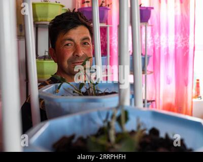 230325 -- TAXKORGAN, 25. März 2023 -- Duri Jarman überprüft dendrobium officinale, das in seinem Haus im Aimin-Dorf des autonomen Bezirks Taxkorgan Tadschik, Nordwestchina, Xinjiang Uygur, angepflanzt wurde, 26. Juni 2019. Das Leben des Hirten Duri Jarman ist eng mit zwei Orten verbunden: Dem Dorf Ak toga Langar, das tief in den Bergen des autonomen Bezirks Taxkorgan Tadschik liegt, und dem Dorf Aimin, das sich in der Nähe des Verwaltungssitzes befindet. Duri, heute 52 Jahre alt, lebte 47 Jahre im Dorf Ak toga Langar. Im Winter 2018 profitierte seine Familie von der Umsiedlungspolitik zur Armutsbekämpfung Stockfoto