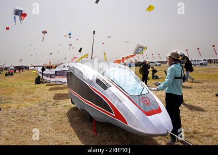 230415 -- WEIFANG, 15. April 2023 -- Menschen versuchen, während des 40. Internationalen Weifang Kite Festivals in Weifang, der ostchinesischen Provinz Shandong, am 15. April 2023, einen eisenbahnförmigen Drachen zu fliegen. Der Drachenfliegerwettbewerb des 40. Internationalen Kite Festivals in Weifang startete hier am Samstag. CHINA-SHANDONG-WEIFANG-KITE FESTIVAL CN LIXZIHENG PUBLICATIONXNOTXINXCHN Stockfoto