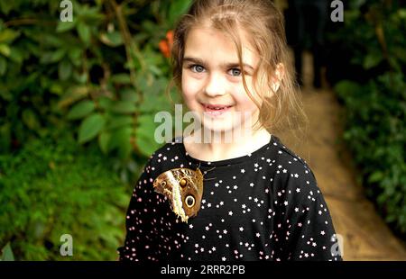 230427 -- PRAG, 27. April 2023 -- Ein Schmetterling sitzt auf Mädchenkleidung während einer tropischen Schmetterlingsausstellung im Botanischen Garten in Prag, Tschechische Republik, am 27. April 2023. Foto von /Xinhua CZECH REPUBLIC-PRAGUE-BUTTERFLY-AUSSTELLUNG DanaxKesnerova PUBLICATIONxNOTxINxCHN Stockfoto