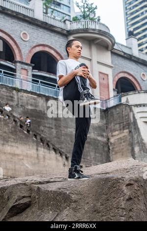 230510 -- PEKING, 10. Mai 2023 -- Wen Shunyao erwärmt sich am 21. April 2023 um den Chaotianmen-Kai in der südwestchinesischen Gemeinde Chongqing. Chongqing, eine Stadt, die auf Bergen erbaut wurde, bietet eine Stadtlandschaft aus Höhen und Tiefen und verstreuten Gebäuden. Die Straße wird oft auf dem Dach gebaut, und die Stadtbahn verläuft durch die Gebäude in der südwestlichen chinesischen Metropole. Mit den natürlichen Vorteilen des Parkour, auch bekannt als Free-Running, bietet Chongqing den Praktizierenden des Parkour einen Spielplatz, auf dem sie Hindernisse in der städtischen Landschaft überwinden, ohne unterstützende Ausrüstung darin zu haben Stockfoto