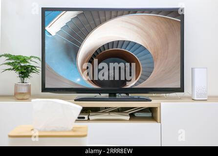 Fernsehen und Filme ansehen und streamen, abstraktes Konzept, Ego-Perspektive, TV-Bildschirm im Hintergrund mit Wendeltreppe den Kaninchenholm hinunter Stockfoto