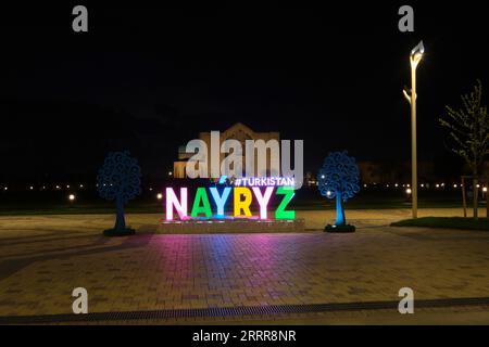 Nächtliche Sicht auf das Mausoleum von Khoja Ahmed Yasawi mit einem fröhlichen Nayryz, Navruz Festival Schild vor. In Turkestan, Kasachstan. Stockfoto