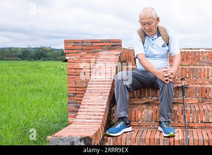 Älterer Mann, der beim Treppensteigen Schmerzen im Knie mit der Hand hält Stockfoto