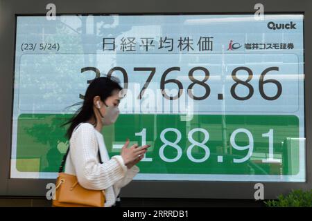 230524 -- TOKIO, 24. Mai 2023 -- Eine Frau kommt an einem Bildschirm vorbei, der Börseninformationen in Tokio, Japan, zeigt, 24. Mai 2023. Japans Benchmark-Nikkei-Aktienindex schloss am Mittwoch niedriger, als die Anleger nach den jüngsten Markterhöhungen weiterhin Gewinne einhielten, da die Bedenken über die US-Schuldenobergrenze und das Potenzial eines beispiellosen Zahlungsausfalls anhalten. Der Nikkei-Aktiendurchschnitt von 225 ging von Dienstag auf 30.682.68, 275,09 Punkte oder 0,89 Prozent zurück. Der weiter gefasste TOPIx-Index verlor inzwischen 9,09 Punkte oder 0,42 Prozent, um bei 2.152,40 zu schließen. JAPAN-TOKIO-STOCK Stockfoto